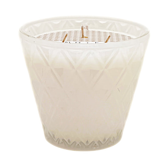A California Beach House white wax candle in a faceted, diamond-patterned clear glass jar with three wicks, shown against a plain white background. SAND + FOG.