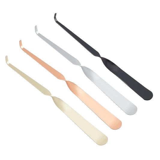 Four twisted metal candle wick dippers in black, silver, rose gold, and gold, arranged diagonally on a solid white background.