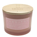 A Sand + Fog candle in a frosted glass jar with a light wood lid, featuring a pink label that reads 'Champagne Toast' and 'Natural Wax Blend'.