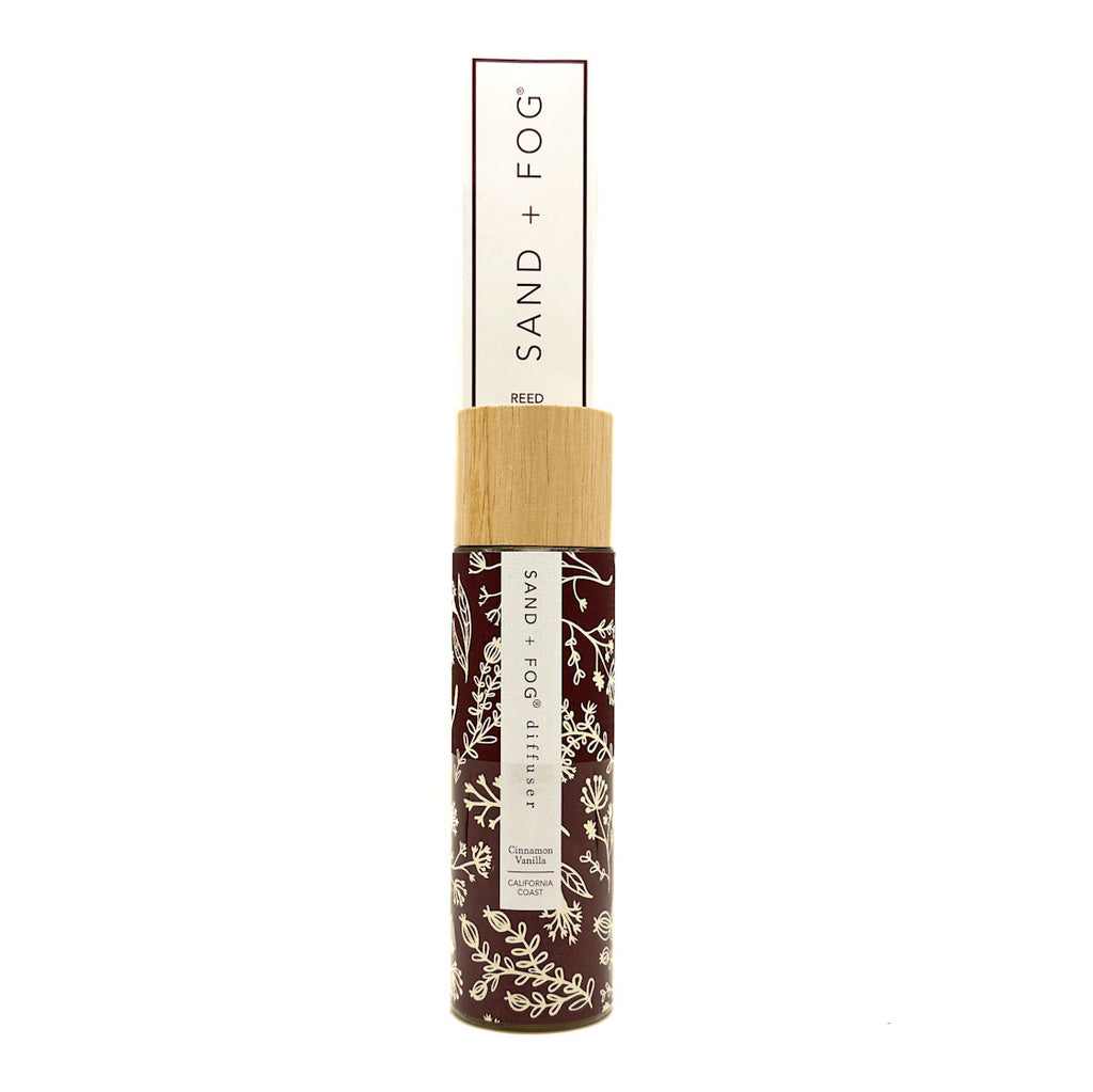 SAND + FOG Cinnamon Vanilla Reed Diffuser with wooden top and floral label on a white background