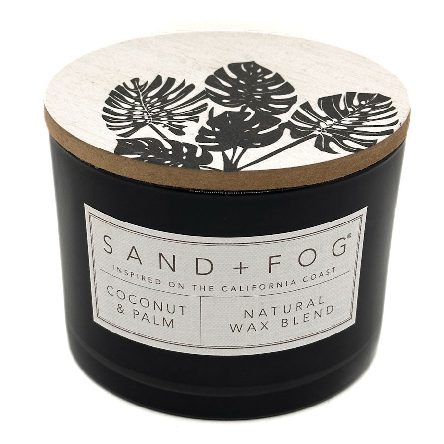 Coconut & Palm black candle with a decorative lid featuring leaf patterns and a visible label on a white background.
