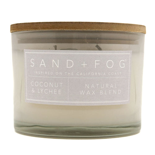 SAND + FOG Coconut & Lychee candle with a wooden lid and label on a white background