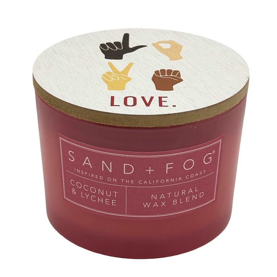 Red candle with a white lid featuring hand signs and 'LOVE.' text, branded as Sand + Fog.