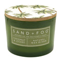 Coconut & Lychee green candle with a decorative lid featuring palm trees, branded 'Sand + Fog'.