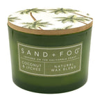 Coconut & Lychee green candle with a decorative lid featuring palm trees, branded 'Sand + Fog'.