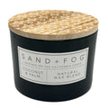 Coconut & Palm black candle with a patterned wooden lid labeled 'Sand + Fog' on a white background