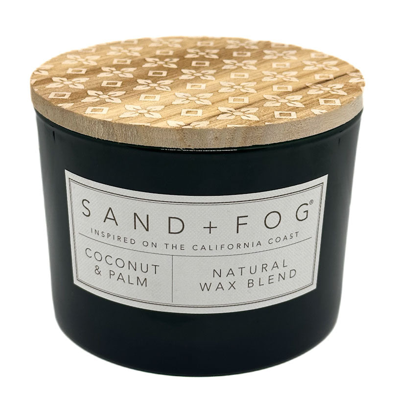 Coconut & Palm black candle with a patterned wooden lid labeled 'Sand + Fog' on a white background