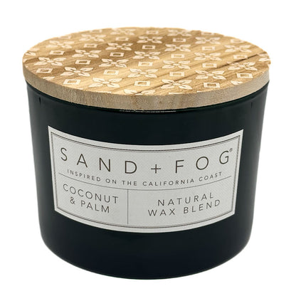 Coconut & Palm black candle with a patterned wooden lid labeled 'Sand + Fog' on a white background