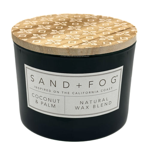 Coconut & Palm black candle with a patterned wooden lid labeled 'Sand + Fog' on a white background