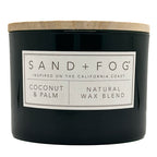 Coconut & Palm Candle black candle with a white label and wooden lid labeled 'Sand + Fog' on a white background