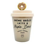 A scented candle designed to look like a cup of creme brulee latte and maple donut with a decorative donut on top.