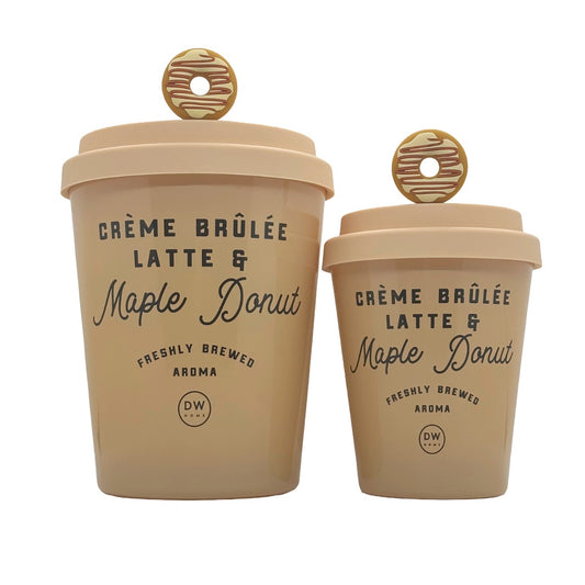 Two beige ceramic coffee cups shaped like latte cups, one large and one small, both with matching lids and round donut-shaped handles. The cups are printed with 'CRÈME BRÛlÉE LATTE & Maple Donut' and a small 'DW' logo, set against a plain white background.