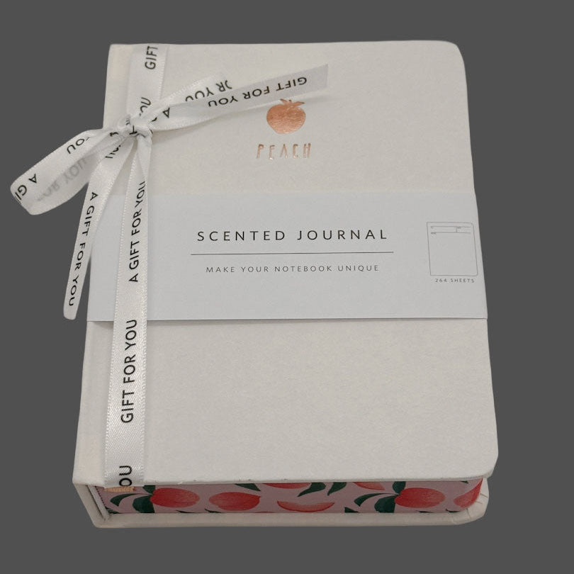 Scented journal with peach design and ribbon on a gray background
