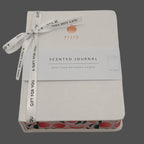 Scented journal with peach design and ribbon on a gray background