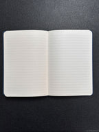 Open notebook with lined pages on a black textured surface