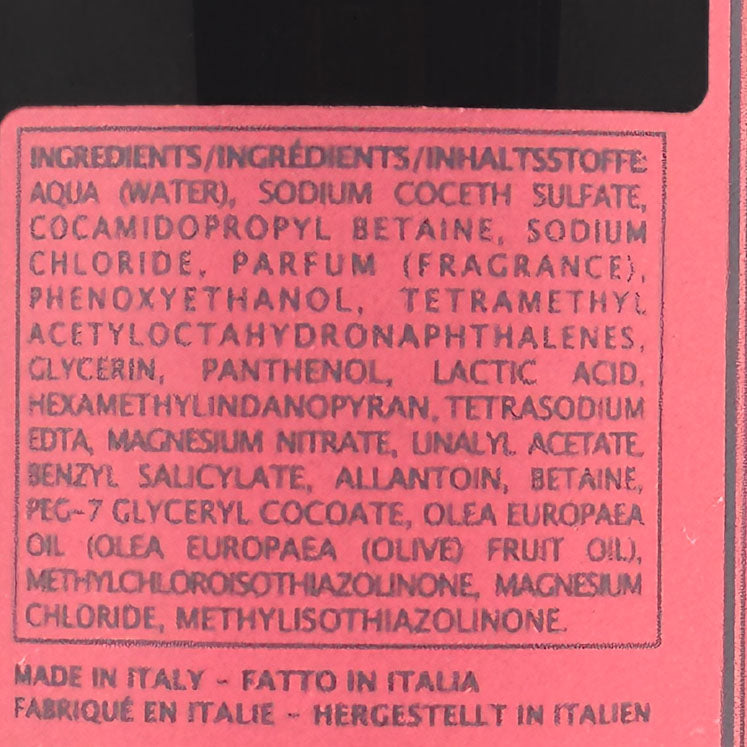 Close-up of a red product label showing the ingredients list in dark purple text, including aqua water, sodium cocoth sulfate, betaine, fragrance, and other additives, with 'Made in Italy' at the bottom.