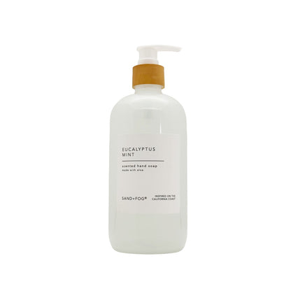 A frosted white pump bottle of Sand+Fog Eucalyptus Mint scented hand soap on a solid white background.