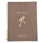 FRINGE brown notebook with gold spiral binding and decorative bow design on a white background