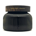 A dark ribbed glass jar with a matching dark wood lid, featuring the words 'FALLING LEAVES' in gold lettering, set against a plain white background.