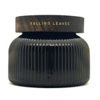 A dark ribbed glass jar with a matching dark wood lid, featuring the words 'FALLING LEAVES' in gold lettering, set against a plain white background.