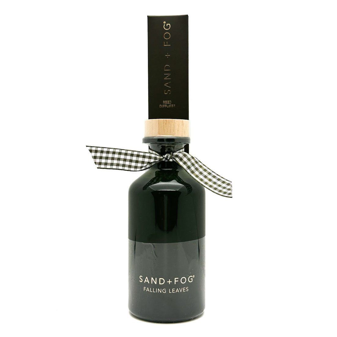 A dark glass bottle of Sand + Fog Falling Leaves reed Diffuser with a black cap, a light wood collar, and a black and white gingham ribbon bow, on a white background.