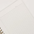 Close-up of a lined notebook page with a gold binding.
