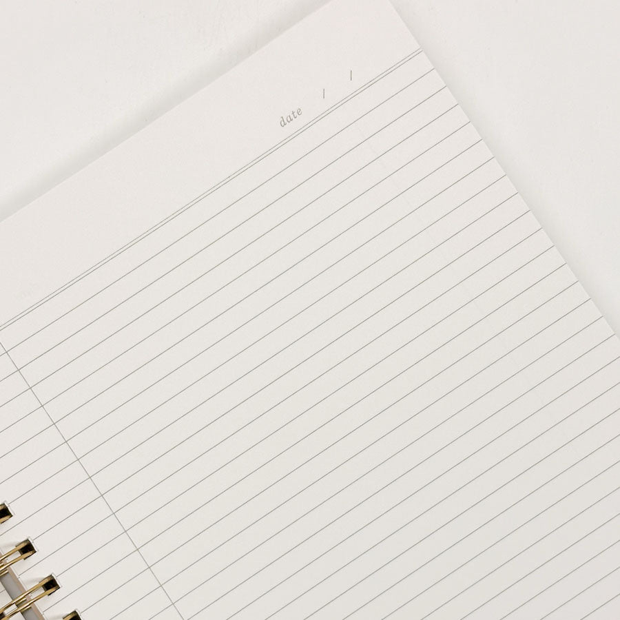Close-up of a lined notebook page with a gold binding.