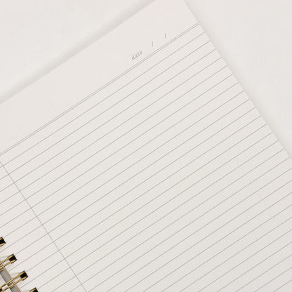 Close-up of a lined notebook page with a gold binding.