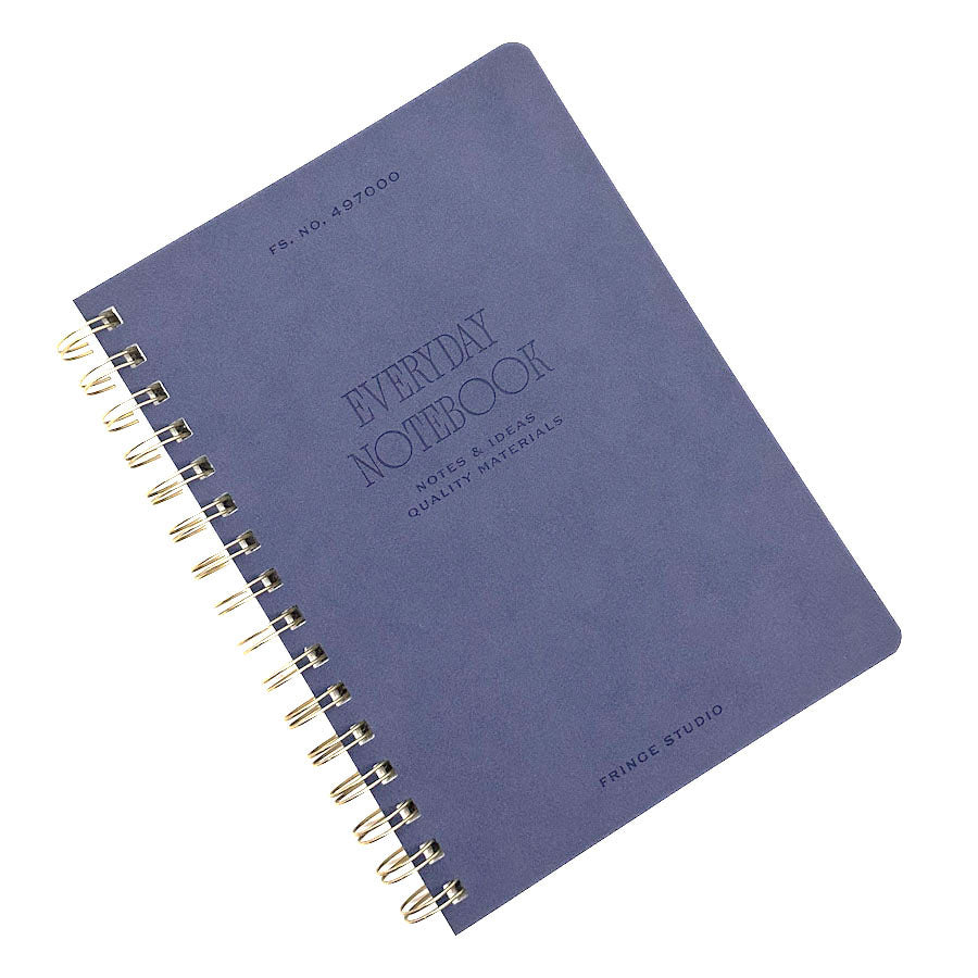 A Fringe Studio spiral-bound notebook with a textured slate blue cover, featuring gold-toned wire binding and embossed text including 'EVERYDAY NOTEBOOK' and 'PRINCE STUDIO'.