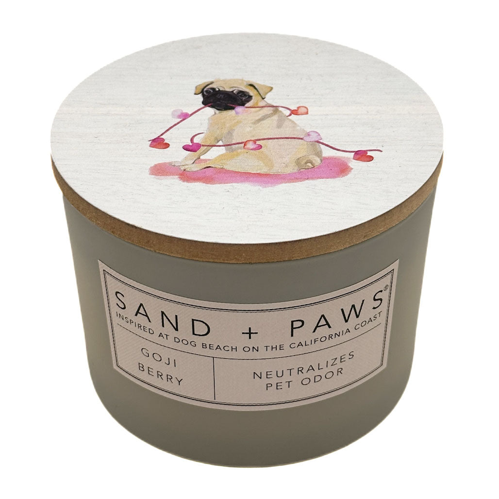 Goji Berry candle with a pug illustration on the lid and 'Sand + Paws' branding.