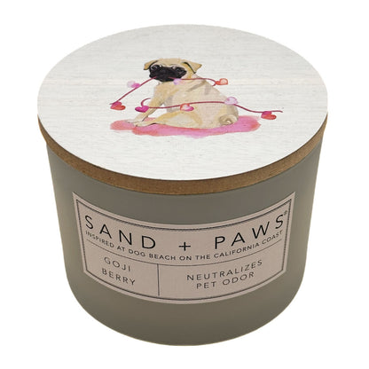 Goji Berry candle with a pug illustration on the lid and 'Sand + Paws' branding.