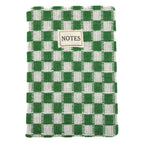 A woven notebook with a green and white checkered pattern, featuring a small beige label on the front that reads 'NOTES'.