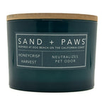 Honeycrisp green candle labeled 'Sand + Paws' with a wooden lid on a white background