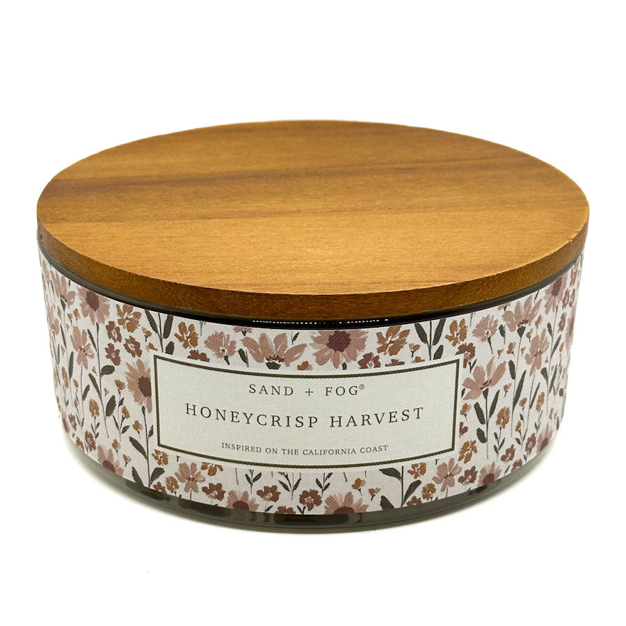 Honeycrisp candle with floral label and wooden lid on a white background