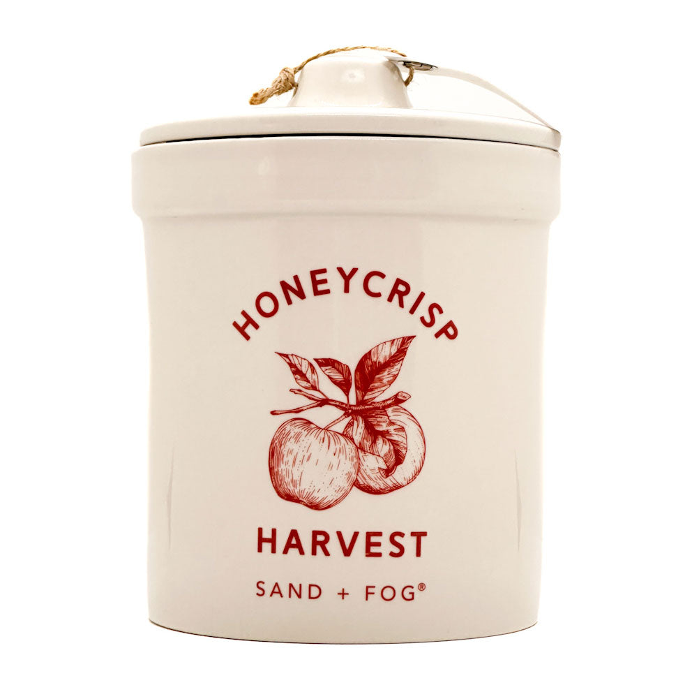 Ceramic candle container with 'Honeycrisp Harvest' design and 'Sand + Fog' branding on a white background