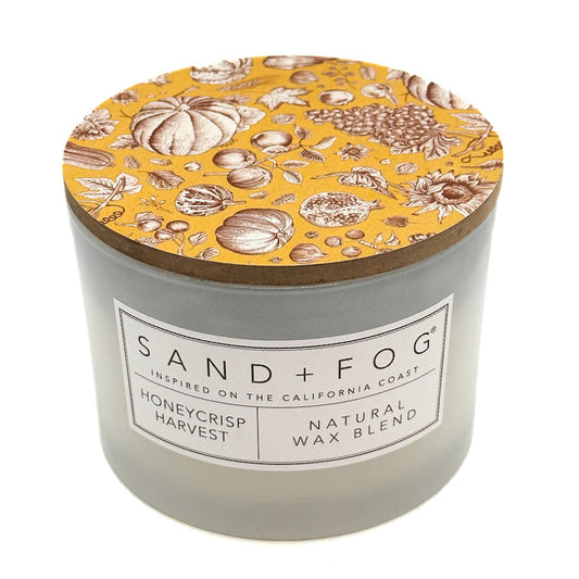 Honeycrisp Harvest Scented Candle with a lid featuring pumpkins and a label branded SAND + FOG.