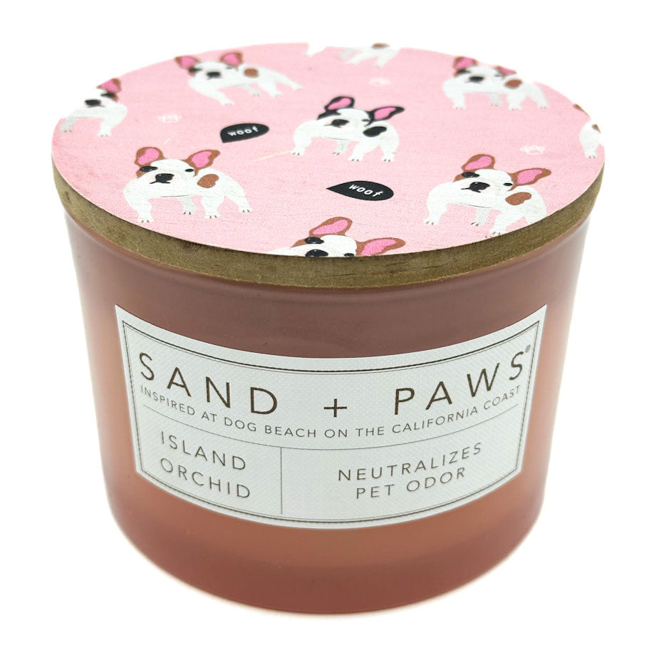 Island Orchid Candle with a pink lid featuring dog illustrations and 'Sand + Paws' branding.