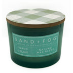Island Orchid green candle with a checkered lid labeled 'Sand + Fog' on a white background