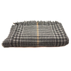 A folded plaid scarf or shawl in black and white with a thin beige stripe down the center and fringed edges, shown on a plain white background.
