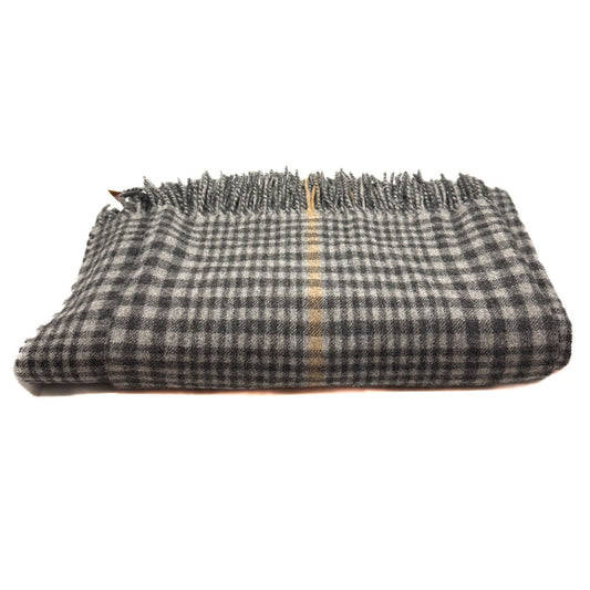 A folded plaid scarf or shawl in black and white with a thin beige stripe down the center and fringed edges, shown on a plain white background.