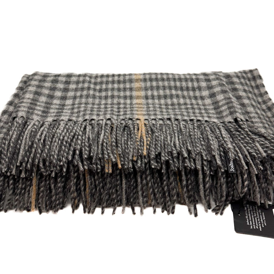 A folded plaid scarf with fringed edges in grey, black, and beige tones, shown on a white background with a small black product tag attached.