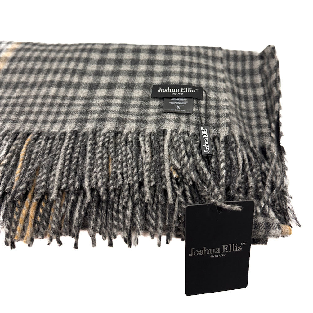A folded plaid fringed scarf in gray, black, and white with subtle tan accents, featuring a Joshua Ellis label and a black product tag on a white background.