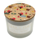Juniper Berry Sage Christmas Candle with a decorative lid featuring dog illustrations and a visible SAND + PAWS brand label.