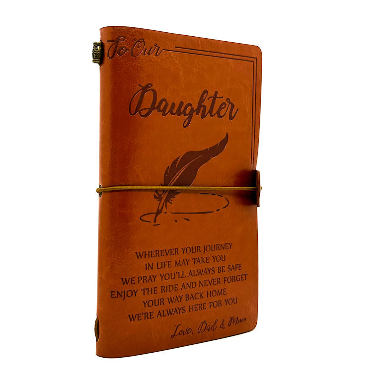 Brown leather journal with engraved text and a feather illustration on a white background