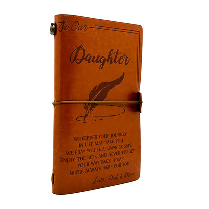 Brown leather journal with engraved text and a feather illustration on a white background