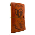 Brown leather journal with engraved message and design on a white background