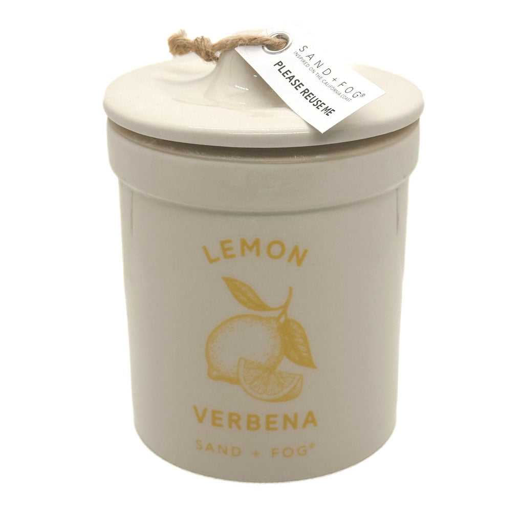 A ceramic jar candle with a matching lid, featuring a yellow lemon illustration and the text 'LEMON VERBENA' on a white background. A small paper tag is attached to the lid with a jute string.