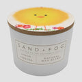 Lemon Verbena candle with a chick design on the lid and 'Sand + Fog' branding.