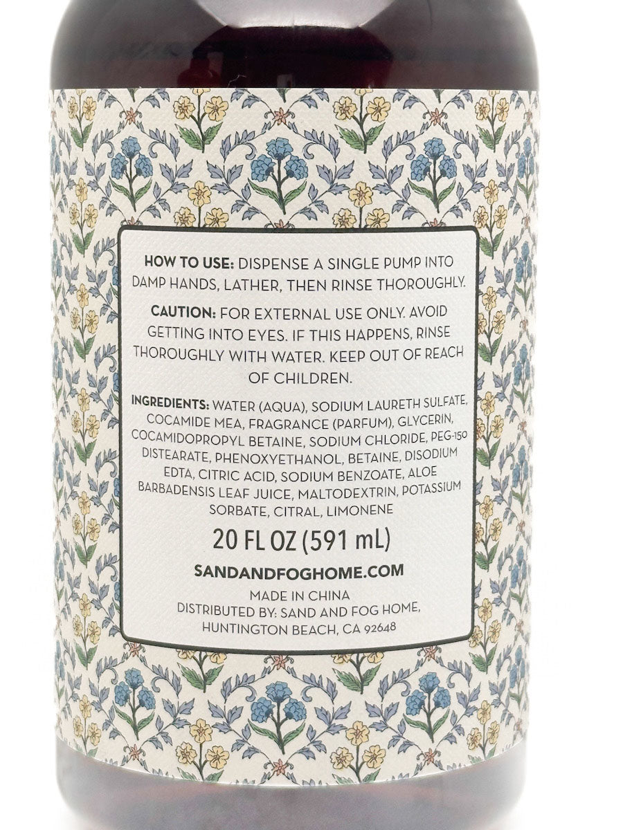 Back label of a Sand and Fog Aromas facial cleansing product, showing usage instructions, ingredients, and product details on a floral patterned background.