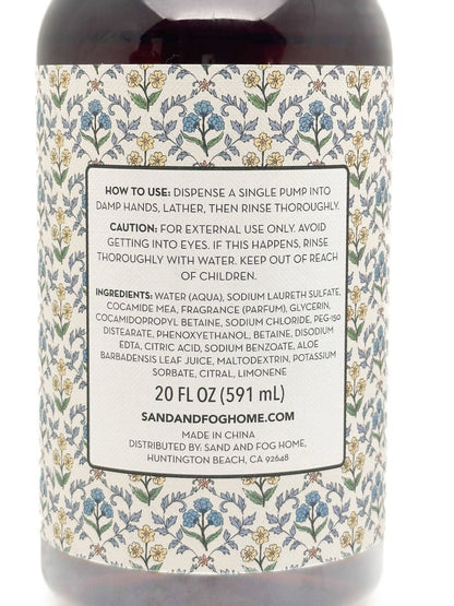 Back label of a Sand and Fog Aromas facial cleansing product, showing usage instructions, ingredients, and product details on a floral patterned background.
